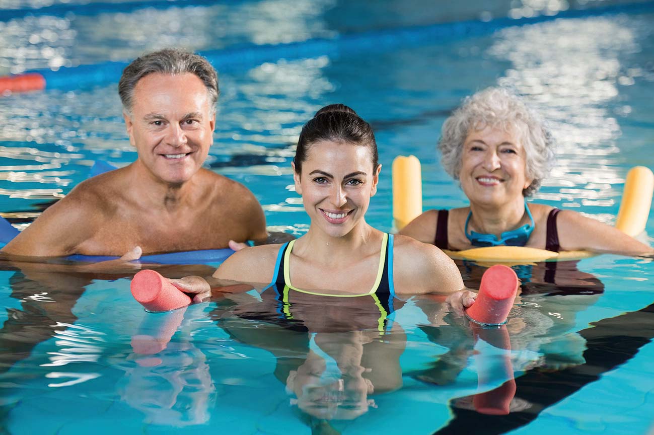 adults in a swimming pool with floatation equipment
